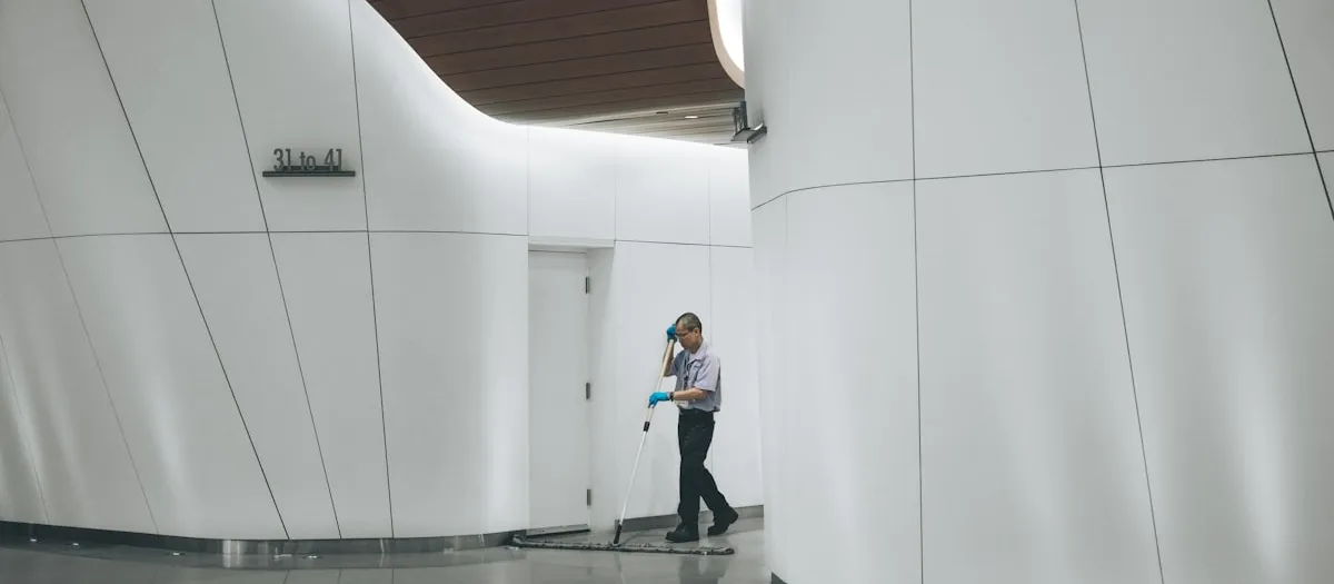 Limpiador profesional trabajando en el pasillo de un edificio moderno
